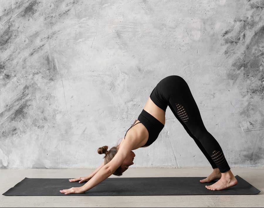 Mujer practicando Yoga Postura del Perro boca abajo